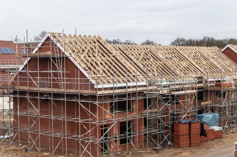 Row of pre-construction homes with exposed rooves and scaffolding